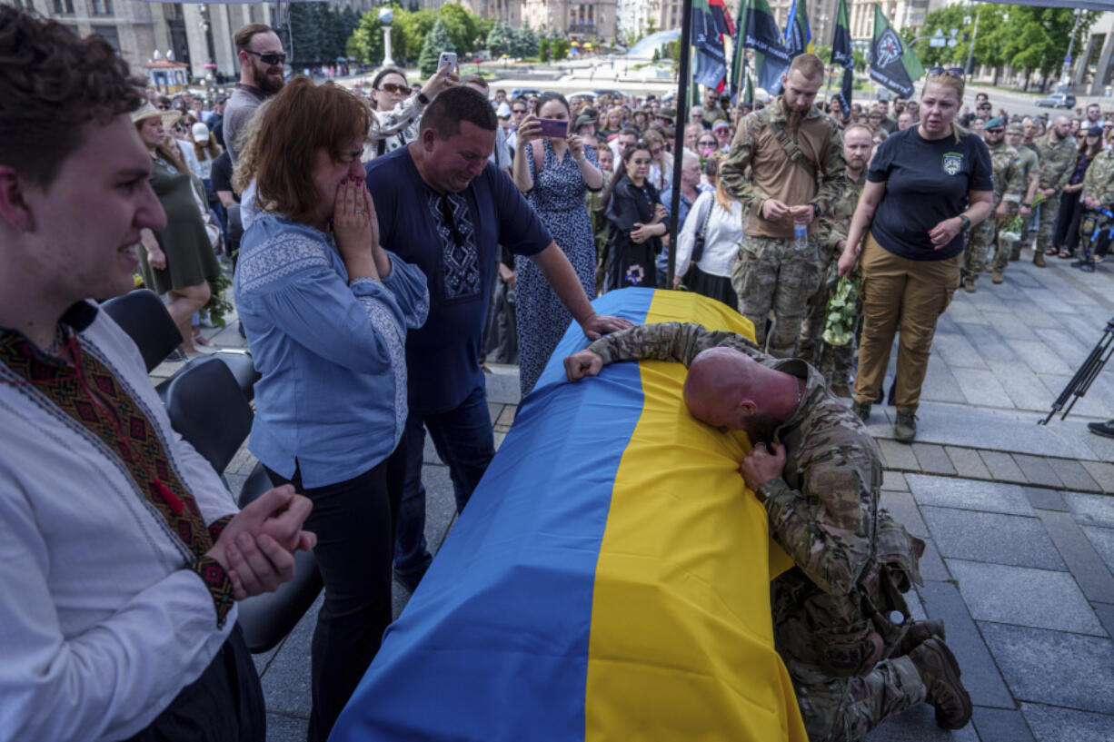 A Ukrainian serviceman cries over the coffin of Ukrainian journalist and volunteer combat medic Iryna Tsybukh during  a memorial service on Independence square in Kyiv, Ukraine, Sunday, June 2, 2024. Nearly 1,000 people attended a ceremony Sunday honoring the memory of Ukrainian journalist Iryna Tsybukh, who was killed in action while serving as a combat medic a few days before her 26th birthday. Tsybukh was killed while on rotation in Kharkiv area, where Russia started its offensive nearly a month ago.