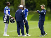 Seattle Seahawks quarterbacks Geno Smith, left, and Sam Howell, back center, stand with quarterbacks coach Charles London, front center, and offensive coordinator Ryan Grubb, right, during an NFL football practice, Monday, June 3, 2024, in Renton, Wash.