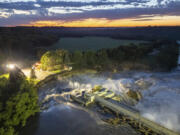 This long-exposure drone photo provided by AW Aerial shows a home as it teeters before partially collapsing into the Blue Earth River at the Rapidan Dam in Rapidan, Minn., Tuesday, June 25, 2024.