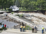 Onlookers take in the catastrophic damage to the Rapidan Dam site in Rapidan, Minn., Monday, June 24, 2024. Debris blocked the dam forcing the heavily backed up waters of the Blue Earth River to reroute along the bank nearest the Dam Store.