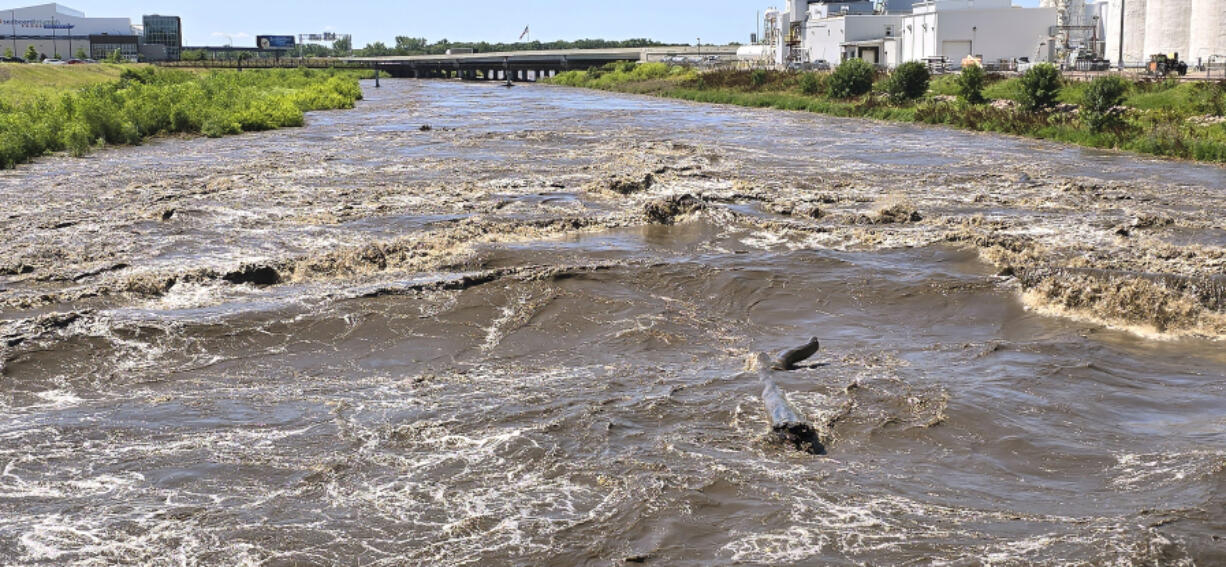 A large log floats downstream as the Floyd River roils past the Dace Avenue bridge in Sioux City, Iowa, Sunday, June 23, 2024. Upstream floodwaters were flowing downstream and into the Missouri River which is expected to crest Tuesday.