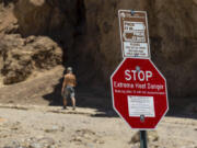 FILE - A hiker passes a sign warning of extreme heat at the start of the Golden Canyon trail, in Death Valley National Park, Calif.,  July 11, 2023. Parts of California, Nevada and Arizona are expected to bake this week as the first heat wave of the season arrives with triple-digit temperatures forecast for areas including Phoenix, which last summer saw a record 31 straight days of at least 110 degrees Fahrenheit (43.3 Celsius).