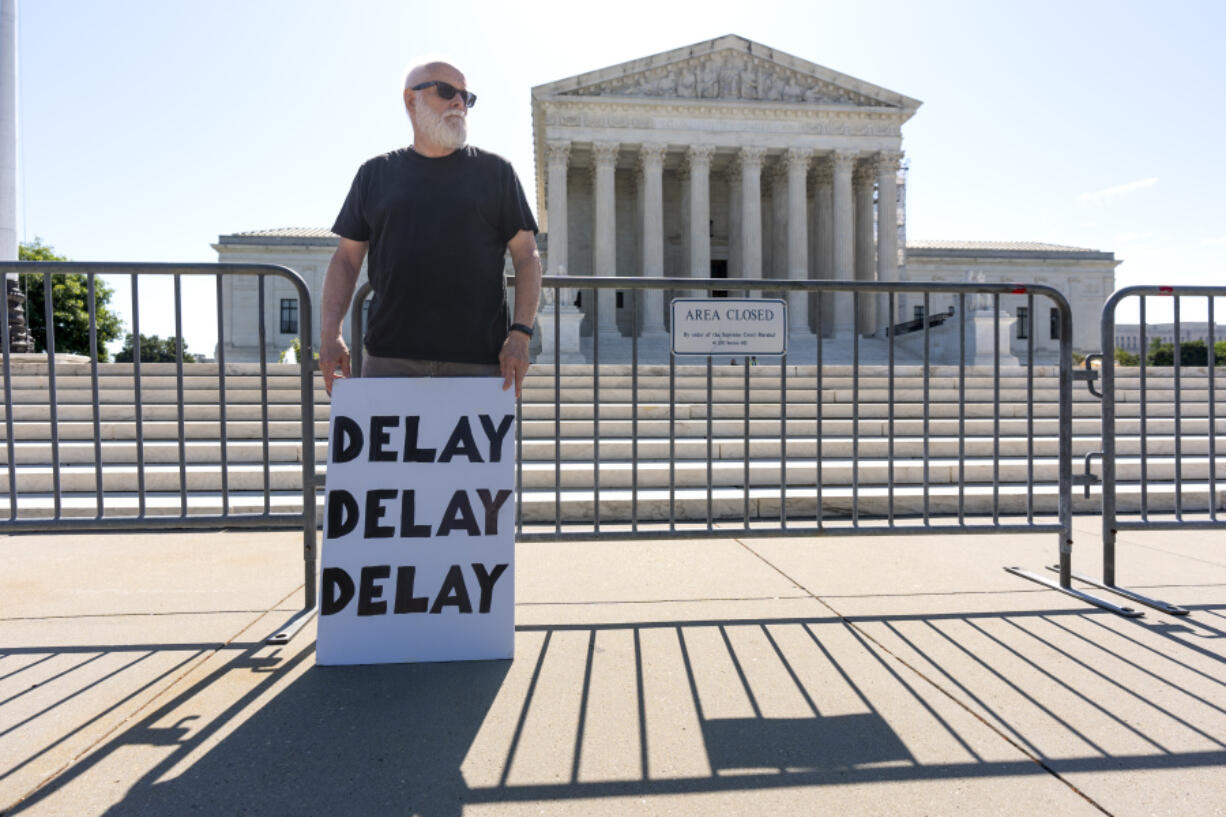 Activist Bill Christeson protests in front of the Supreme Court as decisions are announced, on Capitol Hill in Washington, Friday, June 21, 2024. The justices are still weighing whether former President Donald Trump is immune from criminal prosecution in the election interference case against him, roughly two months after hearing arguments. (AP Photo/J.