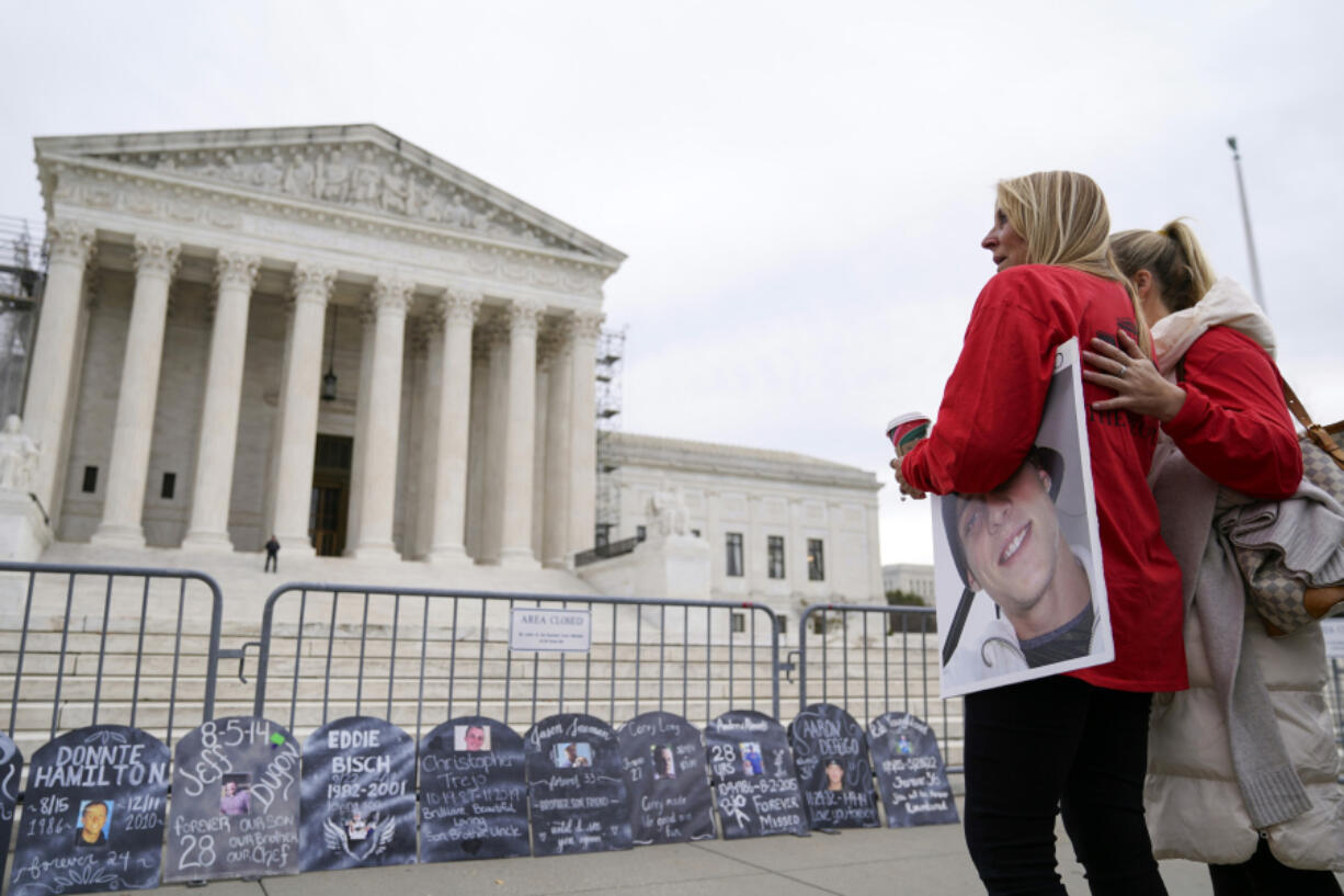 FILE - Jen Trejo holds a photo of her son Christopher as she is comforted outside the Supreme Court where signs in the shape of grave headstones, with information on people who died from using OxyContin, line a security fence, Monday, Dec. 4, 2023, in Washington. The Supreme Court on Thursday, June 27, 2024, rejected a nationwide settlement with OxyContin maker Purdue Pharma that would have shielded members of the Sackler family who own the company from civil lawsuits over the toll of opioids but also would have provided billions of dollars to combat the opioid epidemic.