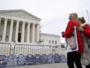 FILE - Jen Trejo holds a photo of her son Christopher as she is comforted outside the Supreme Court where signs in the shape of grave headstones, with information on people who died from using OxyContin, line a security fence, Monday, Dec. 4, 2023, in Washington. The Supreme Court on Thursday, June 27, 2024, rejected a nationwide settlement with OxyContin maker Purdue Pharma that would have shielded members of the Sackler family who own the company from civil lawsuits over the toll of opioids but also would have provided billions of dollars to combat the opioid epidemic.