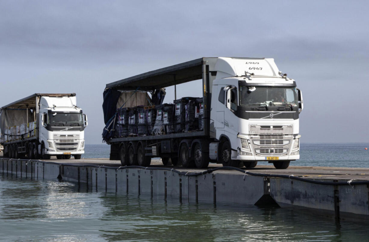 FILE - This image provided by the U.S. Army shows trucks loaded with humanitarian aid from the United Arab Emirates and the United States Agency for International Development cross the Trident Pier before arriving on the beach on the Gaza Strip, May 17, 2024. The U.S.-built pier to bring food to Gaza is facing one of its most serious challenges yet. The United Nations is deciding if it can keep safely delivering supplies from the U.S. sea route to starving Palestinians (Staff Sgt. Malcolm Cohens-Ashley/U.S.