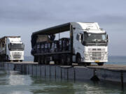 FILE - This image provided by the U.S. Army shows trucks loaded with humanitarian aid from the United Arab Emirates and the United States Agency for International Development cross the Trident Pier before arriving on the beach on the Gaza Strip, May 17, 2024. The U.S.-built pier to bring food to Gaza is facing one of its most serious challenges yet. The United Nations is deciding if it can keep safely delivering supplies from the U.S. sea route to starving Palestinians (Staff Sgt. Malcolm Cohens-Ashley/U.S.