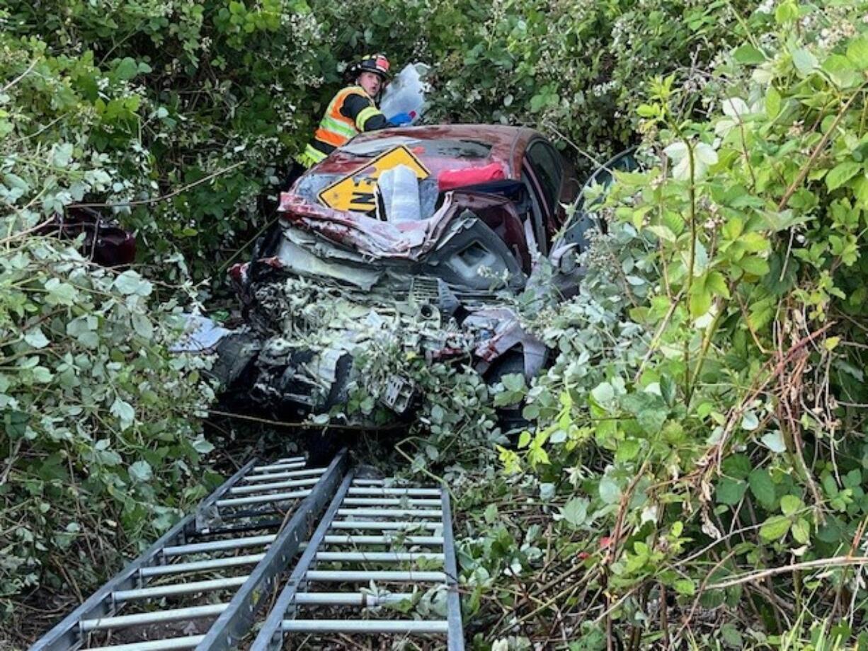 A first responder with the Vancouver Fire Department tends to a vehicle that went down an embankment during a two-vehicle crash on Lower River Road at roughly 8 p.m. on Saturday, June 22, 2024.