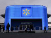 FILE - People walk by the Walmart booth during the CES tech show Tuesday, Jan. 9, 2024, in Las Vegas. Walmart is offering new perks for its hourly workers. They include a new bonus plan as well as opportunities to move into skilled trade jobs within the company.