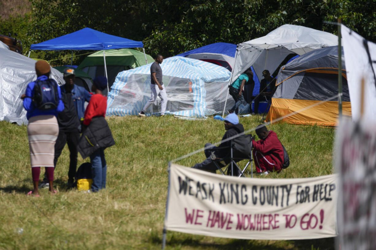 A man walks through an encampment of asylum-seekers mostly from Venezuela, Congo and Angola next to an unused motel owned by the county, Wednesday, June 5, 2024, in Kent, Washington. The group of about 240 asylum-seekers is asking to use the motel as temporary housing while they look for jobs and longer-term accommodations.