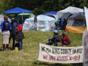 A man walks through an encampment of asylum-seekers mostly from Venezuela, Congo and Angola next to an unused motel owned by the county, Wednesday, June 5, 2024, in Kent, Washington. The group of about 240 asylum-seekers is asking to use the motel as temporary housing while they look for jobs and longer-term accommodations.