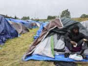 Kunau Eyumu Thierry sits outside his family tent at a camp on Tuesday, June 4, 2024, in Kent, Wash. Asylum seekers who have been looking for shelter in Washington state, mainly from Angola, Congo and Venezuela, have set up an encampment in a Seattle suburb.