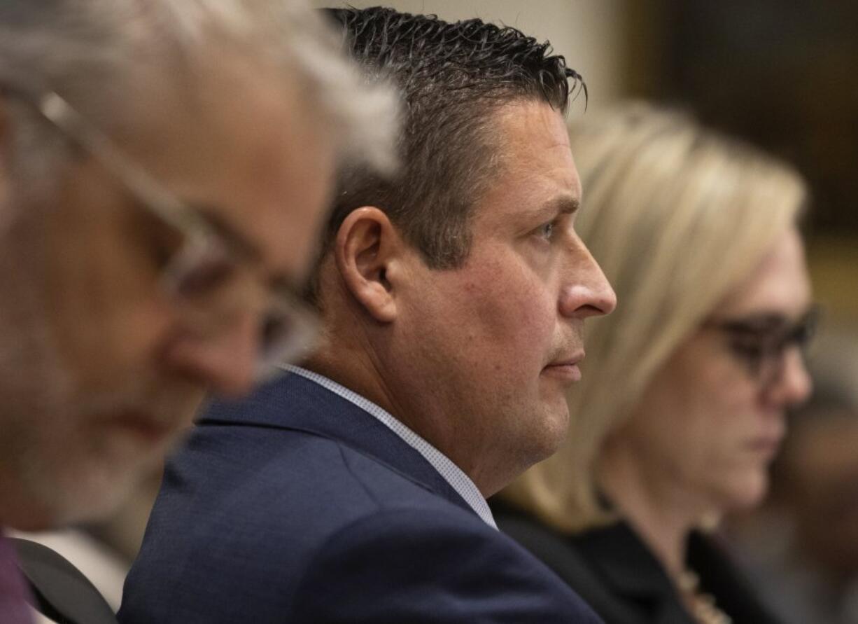 Auburn Police Officer Jeffrey Nelson, center, is flanked by two of his defense attorneys as Nelson&rsquo;s murder trial gets underway, Thursday, May 16, 2024 in Kent, Wash. On the left is Tim Leary, to the right is Emma Scanlan. Nelson is charged with murder in the death of a 26-year-old man outside a convenience store.