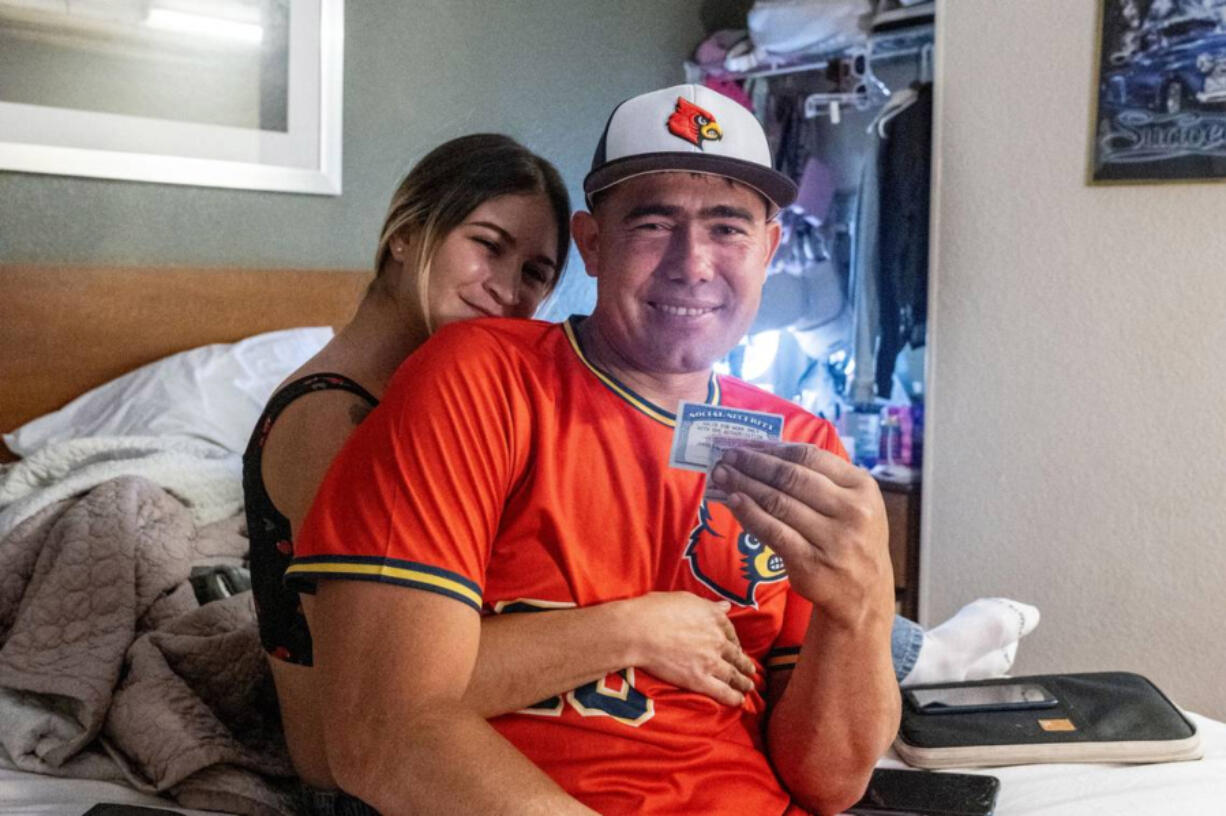 Olglaivis Barrios and Jorge Gil Laguna sit together in their motel room in Sacramento earlier this month. Laguna holds his social security card and work permit he recently received.