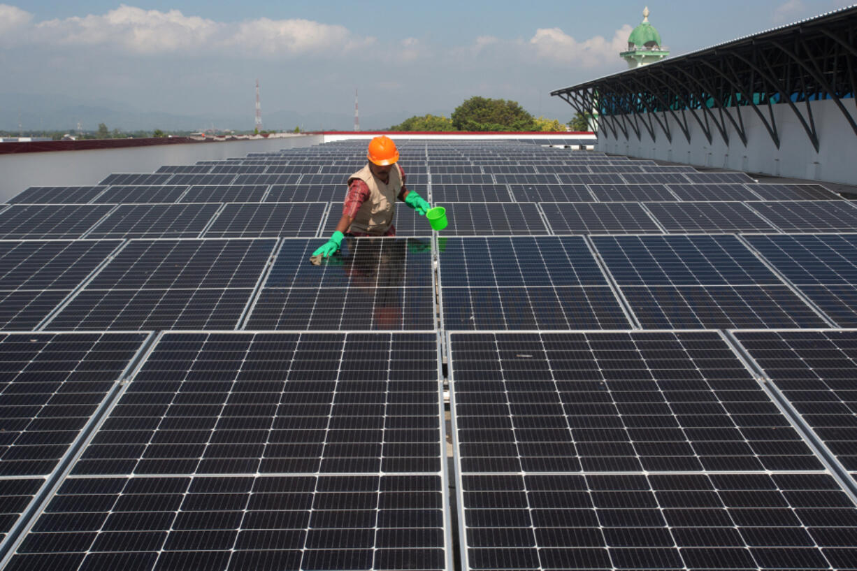 A worker cleans solar panels installed on the roof of the traditional Gedhe market in Klaten, Central Java, June 20, 2024.