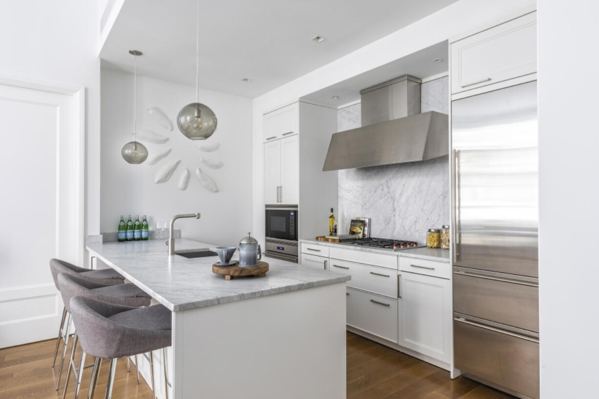 White cabinets paired with a white marble backsplash and countertop help make this open kitchen feel bright and airy.