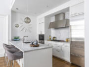 White cabinets paired with a white marble backsplash and countertop help make this open kitchen feel bright and airy.