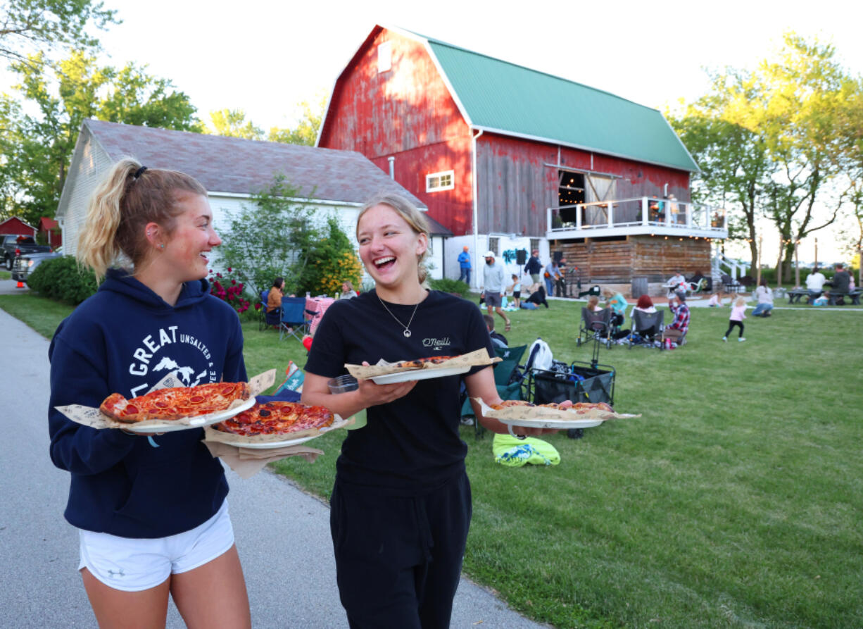 Ashleigh McCarthy, 19, left, and her sister, Calleigh McCarthy, 16, carry pizzas to their family during Farm Pizza night at Mapleton Barn on May 30 in Oconomowoc, Wis.