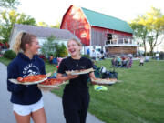 Ashleigh McCarthy, 19, left, and her sister, Calleigh McCarthy, 16, carry pizzas to their family during Farm Pizza night at Mapleton Barn on May 30 in Oconomowoc, Wis.