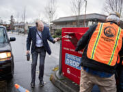 Clark County Auditor Greg Kimsey, left, helps a voter drop off their ballot at the ballot box in downtown Vancouver on March 12.