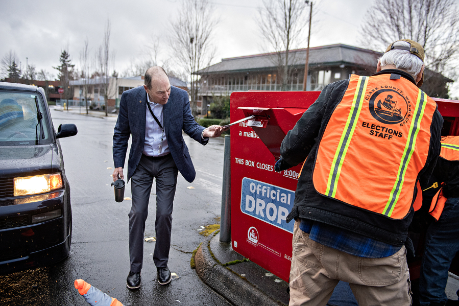 Clark County Auditor Greg Kimsey, left, helps a voter drop off their ballot at the ballot box in downtown Vancouver on March 12.