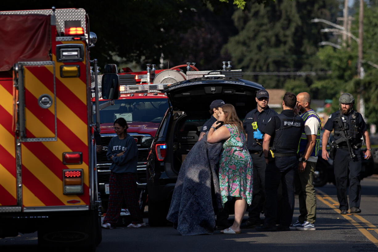 Baylee Gonzales embraces the daughter of Carissa Larkin Thursday morning as first responders work at the scene of an apparent murder-suicide in central Vancouver that left Larkin dead.