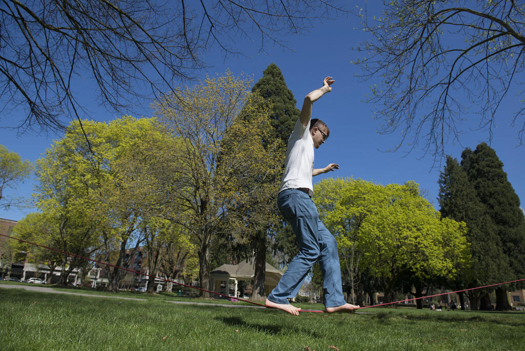 Jeff Way of Vancouver, right, keeps his balance as he enjoys slacklining in the sunshine with his roommate, Matthew Nebel, not pictured, Friday afternoon, April 1, 2016 at Esther Short Park. Yesterday's blue skies and warm temperatures made it a good day for residents to kick off their shoes and get outdoors.