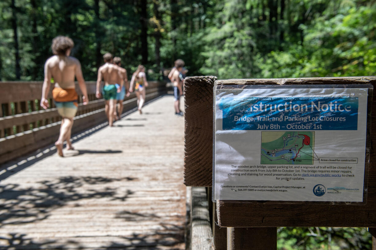 Visitors to Moulton Falls Bridge stroll past a notice of its upcoming closure Friday afternoon. The bridge will close next week for repairs.