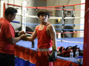 Cain Elizondo, left, laces up boxing gloves for his son, Cain Elizondo Jr., at Young Guns Boxing in Hazel Dell on Wednesday, July 17, 2024. Elizondo Jr., 14, is the nation&rsquo;s top-ranked 125-pounder in his age group in the USA Boxing national rankings.