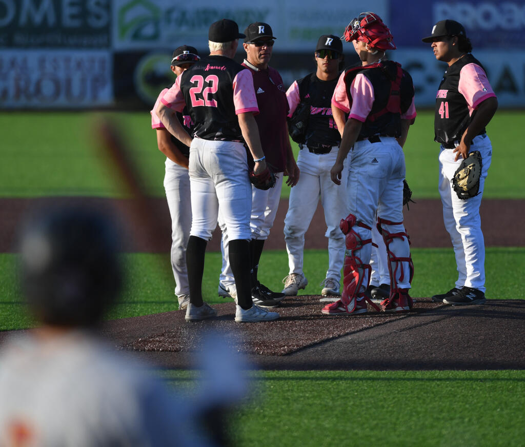 Ridgefield coach Chris Cota, third from left, meets with the infield Thursday, July, 25, 2024, during a game between the Raptors and the Corvallis Knights at the Ridgefield Outdoor Recreation Complex.