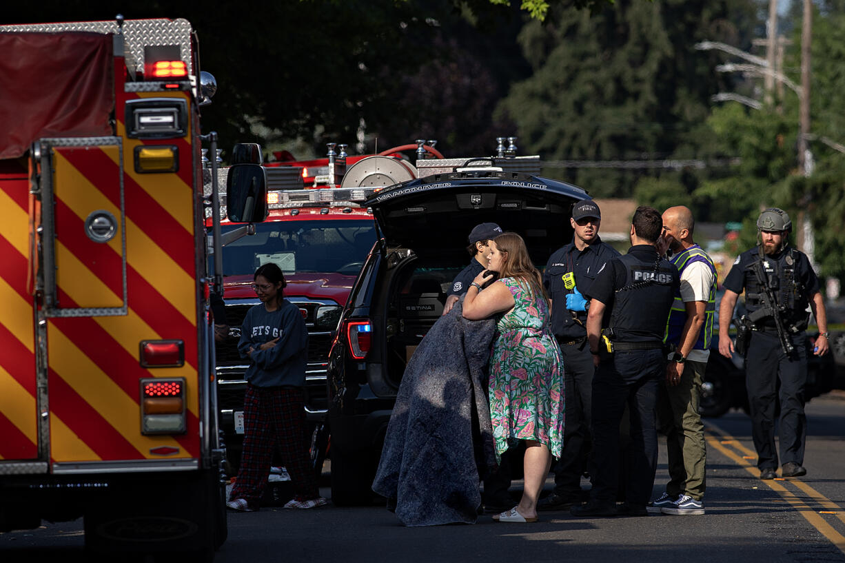 Bystanders embrace as first responders work at the scene after a shooting left two people dead in central Vancouver on Thursday morning, July 25, 2024.