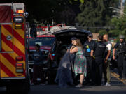 Bystanders embrace as first responders work at the scene after a shooting left two people dead in central Vancouver on Thursday morning, July 25, 2024.