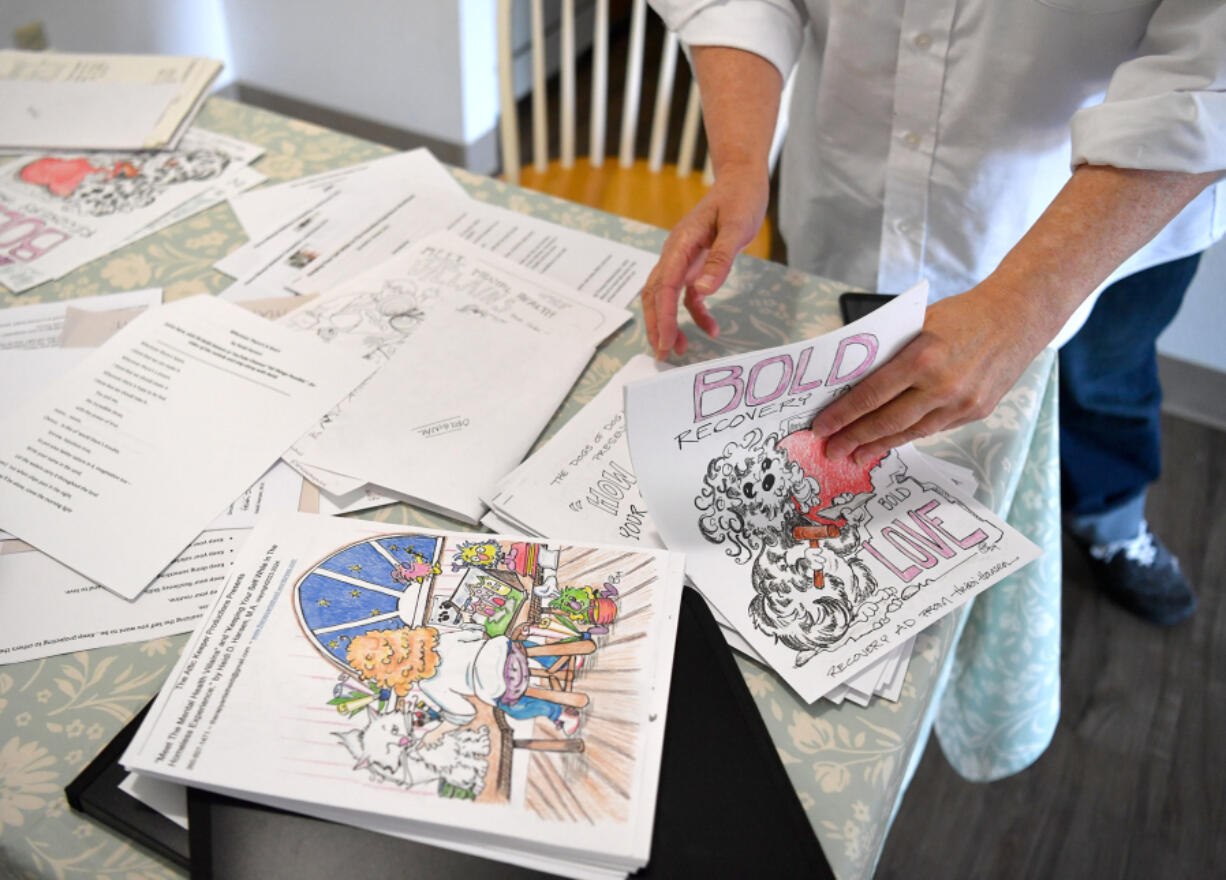 Artist Heidi Hansen looks through stacks of pages from her workbooks Friday at Hansen&rsquo;s apartment in Vancouver. Hansen experienced homelessness for five years and has created a workbook to help people with their mental health challenges.