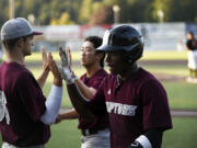 Dasan Harris (foreground) and Taylor Takata (background) of the Ridgefield Raptors are greeted by teammate Curtis Hebert (36) after scoring in the Raptors' West Coast League baseball game against the Cowlitz Black Bears at David Story Field in Longview on Friday, July 26, 2024.