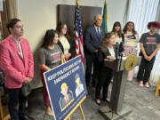 Washington Gov. Jay Inslee, center rear, and abortion rights supporters listen as Dr. Sarah Prager, a professor of obstetrics and gynecology at the University of Washington, speaks to reporters during a news conference in Seattle, Tuesday, June 11, 2024. Inslee announced that Washington state will spell out in state law that hospitals must provide abortions if needed to stabilize patients, a step that comes as the U.S. Supreme Court is expected to rule this month on whether conservative states can bar abortions during some medical emergencies.