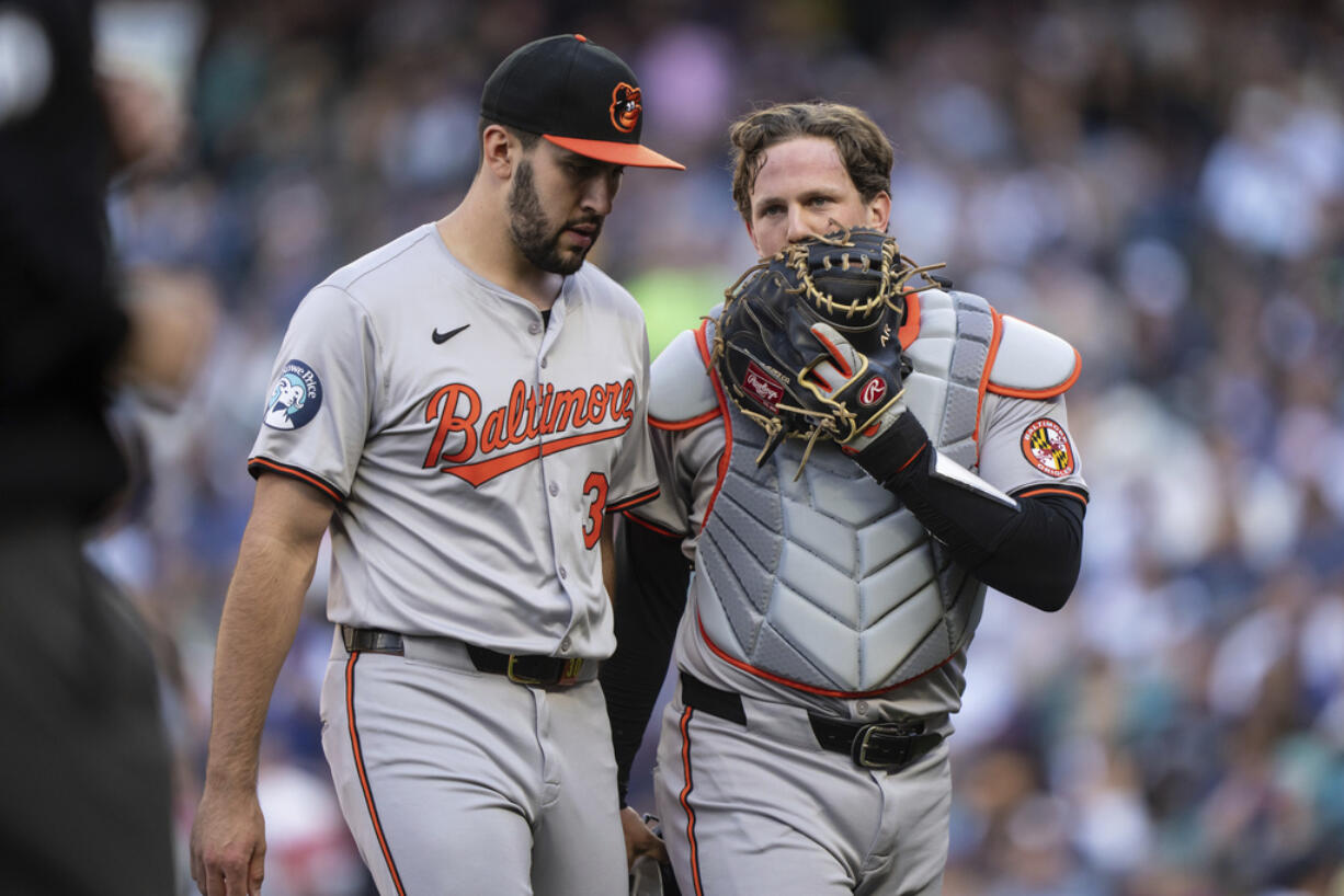 Baltimore Orioles starting pitcher Grayson Rodriguez, left, and catcher Adley Rutschman walk off the field at the end of the first inning of a baseball game against the Seattle Mariners, Tuesday, July 2, 2024, in Seattle.