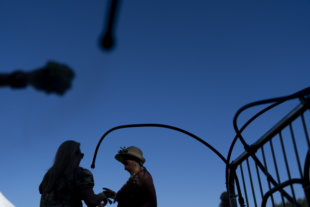 A person reaches to wet a piece of cloth at a misting station as others cool off with the misters during the Waterfront Blues Festival on Friday, July 5, 2024, in Portland, Ore. A slow-moving and potentially record-setting heat wave is spreading across the Western U.S., sending many residents in search of a cool haven from the dangerously high temperatures.