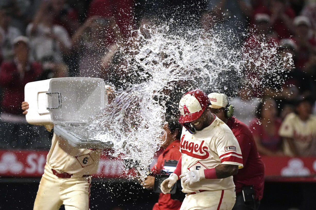 Los Angeles Angels' Willie Calhoun, is hit with water by Anthony Rendon as he scores after hitting a walk-off two-run home run during the 10th inning of a baseball game against the Seattle Mariners Friday, July 12, 2024, in Anaheim, Calif. (AP Photo/Mark J.