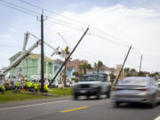 Linemen place a new fiberglass utility pole to replace older, leaning wooden poles along FM 3005 on Galveston Island on Saturday, July 13, 2024.