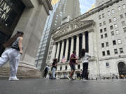 FILE - People pass the New York Stock Exchange July 10, 2024, in New York. World shares began trading mixed on Monday, July 15, 2024, after China reported that its economy expanded at a lower-than-forecast 4.7% annual pace in the last quarter.