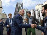 FILE - Democratic Presidential candidate Washington Gov. Jay Inslee, center, greets people as he tours the Blue Plains Advanced Wastewater Treatment Plant in Washington, Thursday, May 16, 2019, during an event where he unveiled part of his plan to defeat climate change.