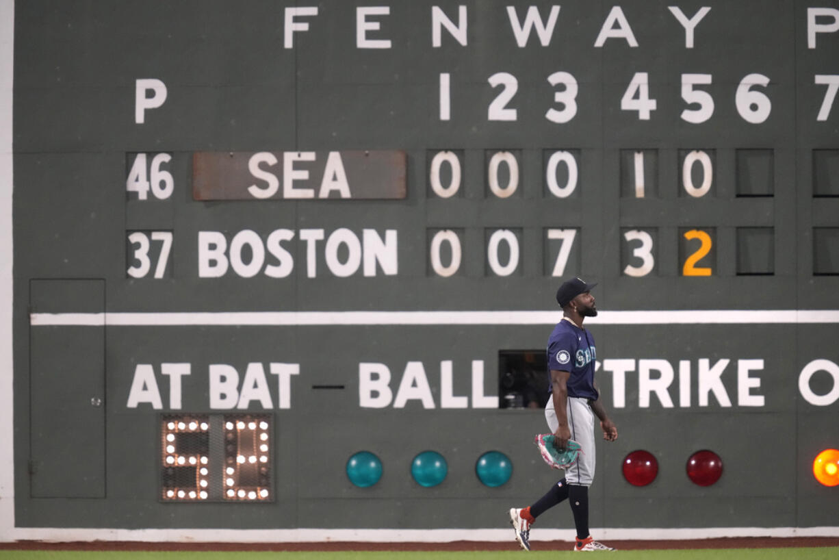 Seattle Mariners left fielder Randy Arozarena walks past the Green Monster scoreboard during the fifth inning of a baseball game against the Boston Red Sox, Monday, July 29, 2024, in Boston.