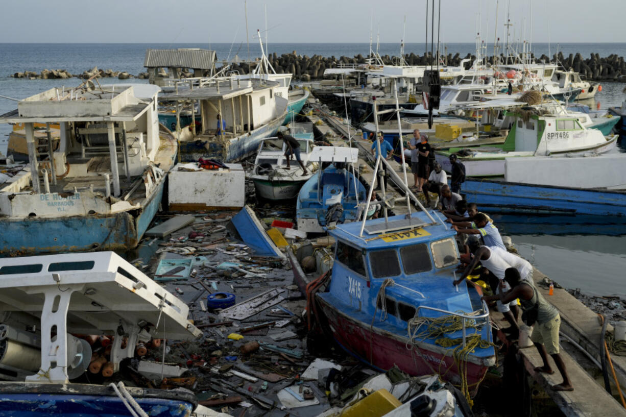 Fishermen push a boat damaged by Hurricane Beryl at the Bridgetown fisheries, Barbados, Tuesday, July 2, 2024.