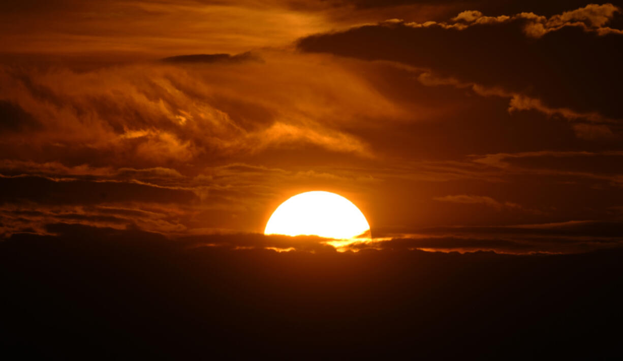 The setting sun illuminates the clouds over the Rocky Mountains after a third straight day of record-breaking heat Sunday, July 14, 2024, in Denver.