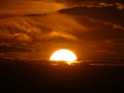 The setting sun illuminates the clouds over the Rocky Mountains after a third straight day of record-breaking heat Sunday, July 14, 2024, in Denver.