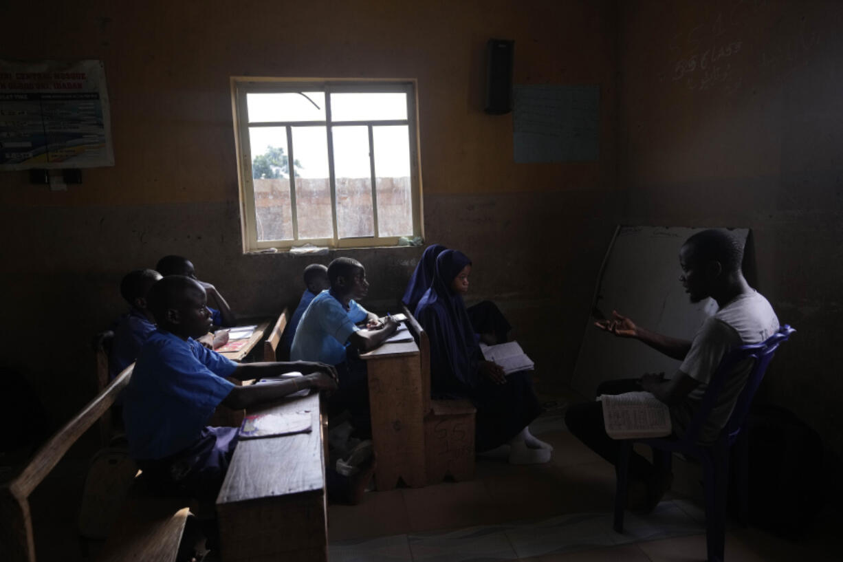 Students of Excellent Moral School attend a lesson in a window-lit classroom in Ibadan, Nigeria, Tuesday, May 28, 2024. Schools like Excellent Moral operate in darkness due to zero grid access, depriving students of essential tools like computers.