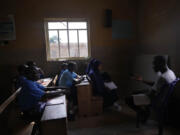 Students of Excellent Moral School attend a lesson in a window-lit classroom in Ibadan, Nigeria, Tuesday, May 28, 2024. Schools like Excellent Moral operate in darkness due to zero grid access, depriving students of essential tools like computers.