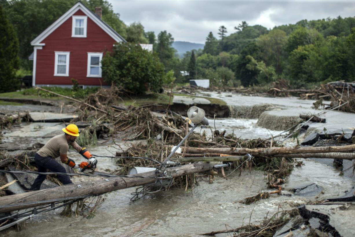 Zac Drown, of Lyndon Electric Company, clears debris amid flood damage in Lyndon, Vt., Tuesday, July 30, 2024.