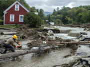 Zac Drown, of Lyndon Electric Company, clears debris amid flood damage in Lyndon, Vt., Tuesday, July 30, 2024.