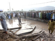 People gather to clear the rubble of a house partially damaged by landslide due to heavy rainfall in Surkhroad district of Jalalabad, Nangarhar province east of Kabul, Afghanistan, Monday, July 15, 2024.